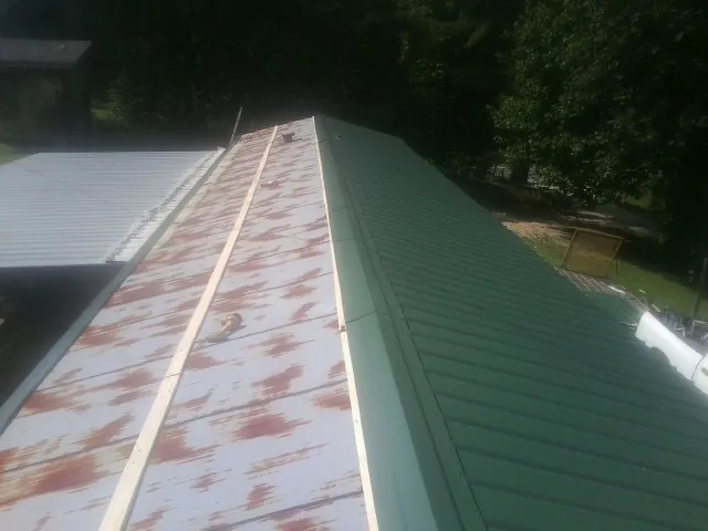 Old rusted panels beside newly installed green metal roofing — Wind Damage Roof Repair by Roofing Brothers in Ponchatoula