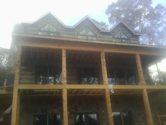 Dormers and porch framing on a large log home under construction — Roof Coating work by our crew in Ponchatoula