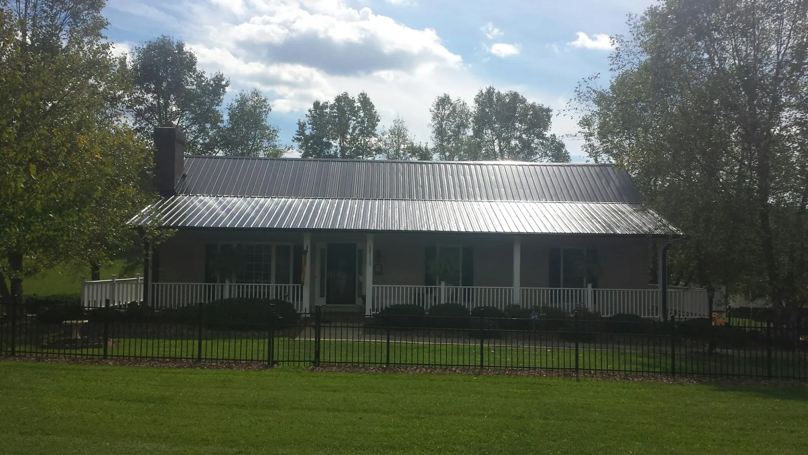 Gray metal roof on a brick ranch with a full width front porch — Gutter Guard Installation work by our crew in Ponchatoula