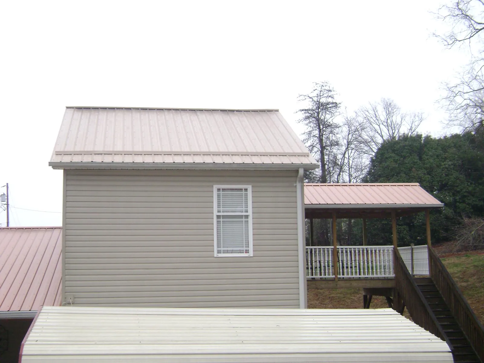 Tan metal roofs on a two story addition and attached porch, from a Roof Replacement job in Ponchatoula
