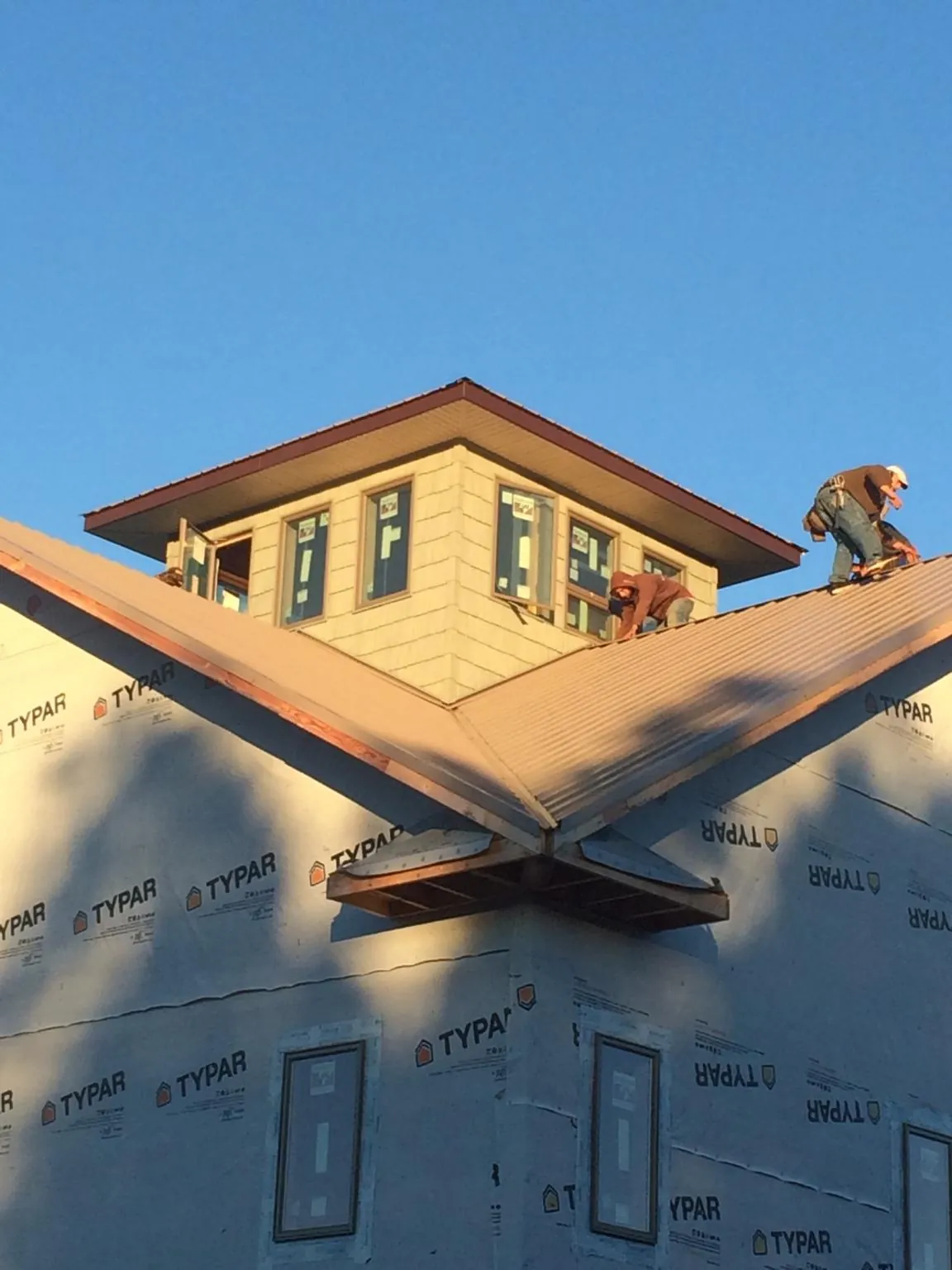 Roofers working around a rooftop cupola on a new metal roof at sunset — Roof Waterproofing in Ponchatoula by Roofing Brothers